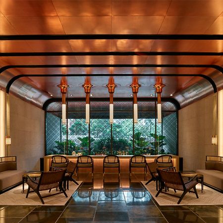 더 루마 호텔 앤 레지던스 쿠알라룸푸르 외부 사진 The image shows a stylish interior space with a modern and elegant design. The walls have a sleek, warm-toned finish, and there are large windows that provide natural light. The ceiling features striking architectural lines, likely in a metallic mate
