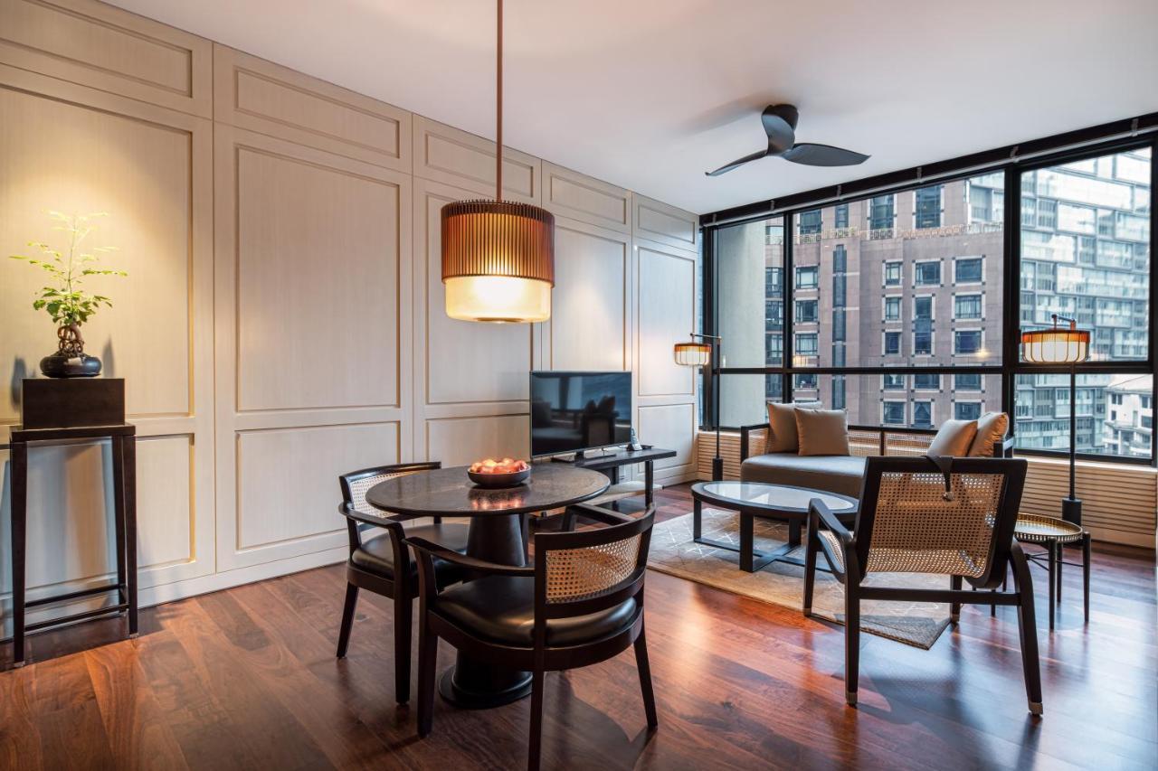 더 루마 호텔 앤 레지던스 쿠알라룸푸르 외부 사진 The photo shows a modern interior living space that features a dining area and a lounge. The dining table is set for four with stylish black chairs. Above the table, there is a pendant light providing illumination. On one side, there is a comfortable