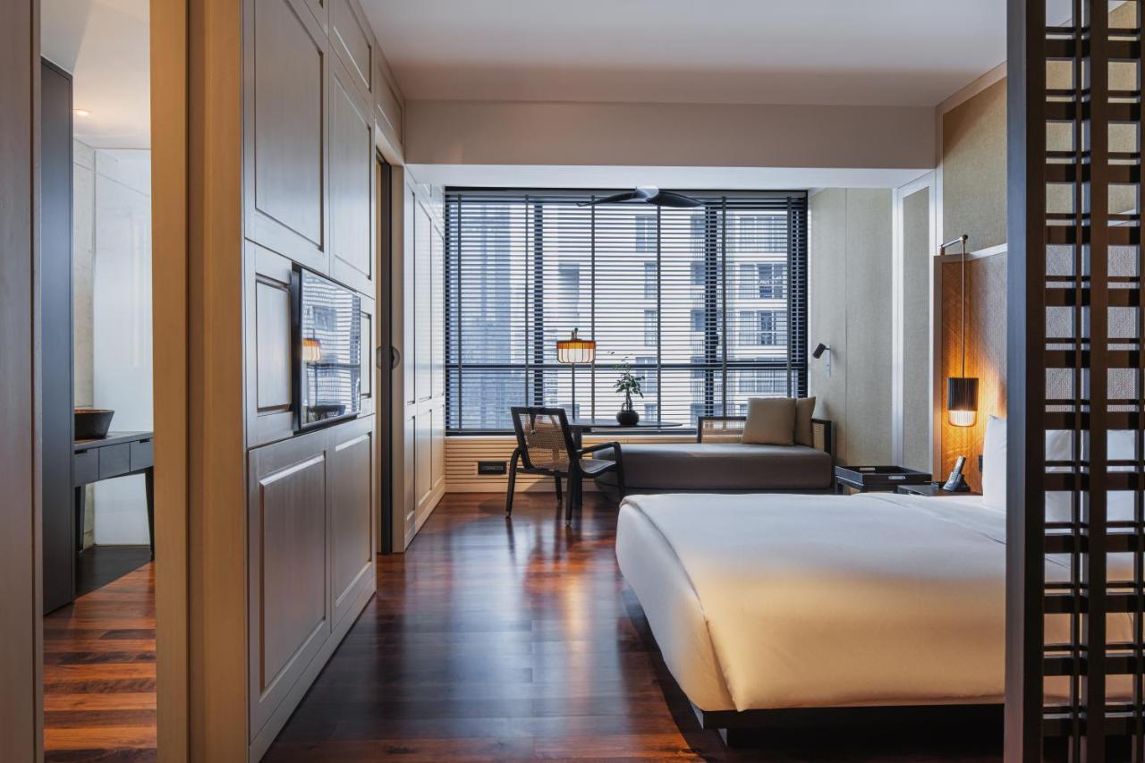 더 루마 호텔 앤 레지던스 쿠알라룸푸르 외부 사진 The photo shows a modern hotel room with a clean and minimalist design. The room features a large bed with white bedding positioned against a wall. There is a wooden floor that adds warmth to the space. A sitting area is visible in the background, fe