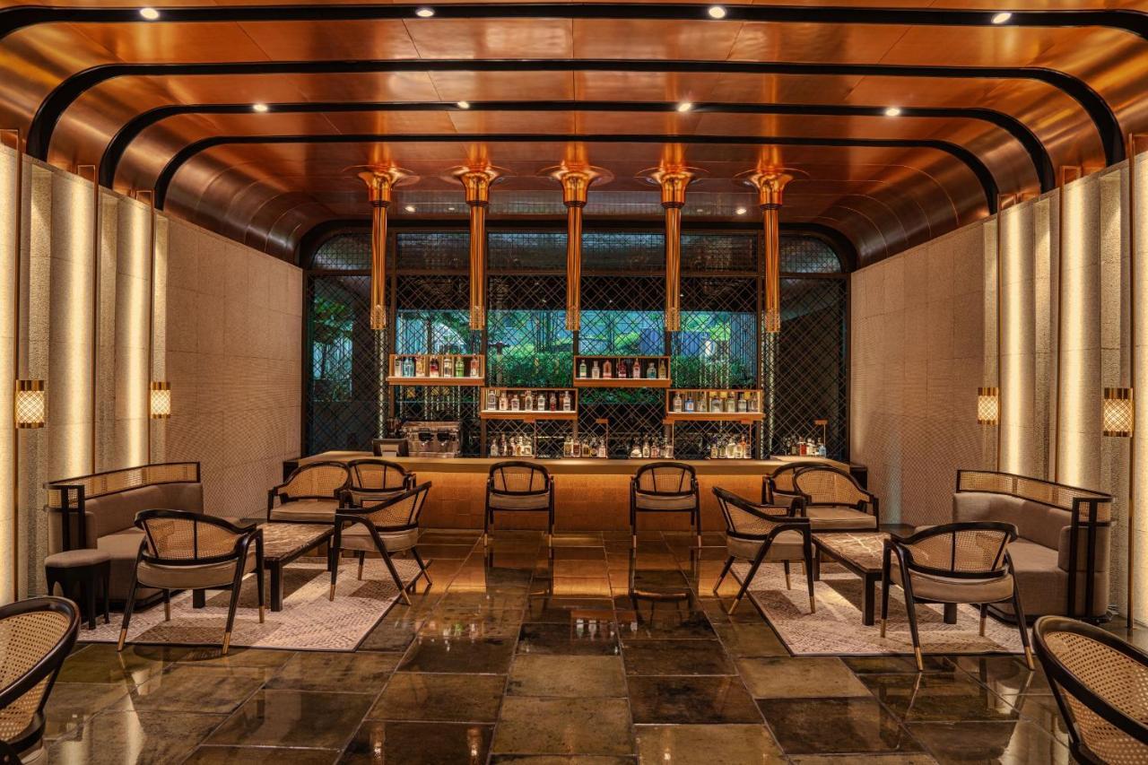 더 루마 호텔 앤 레지던스 쿠알라룸푸르 외부 사진 The photo shows a stylish interior of a bar or lounge area. The space features a combination of elegant materials, including polished metal accents and warm lighting. A wooden bar counter is centrally located, with several shelves displaying various 