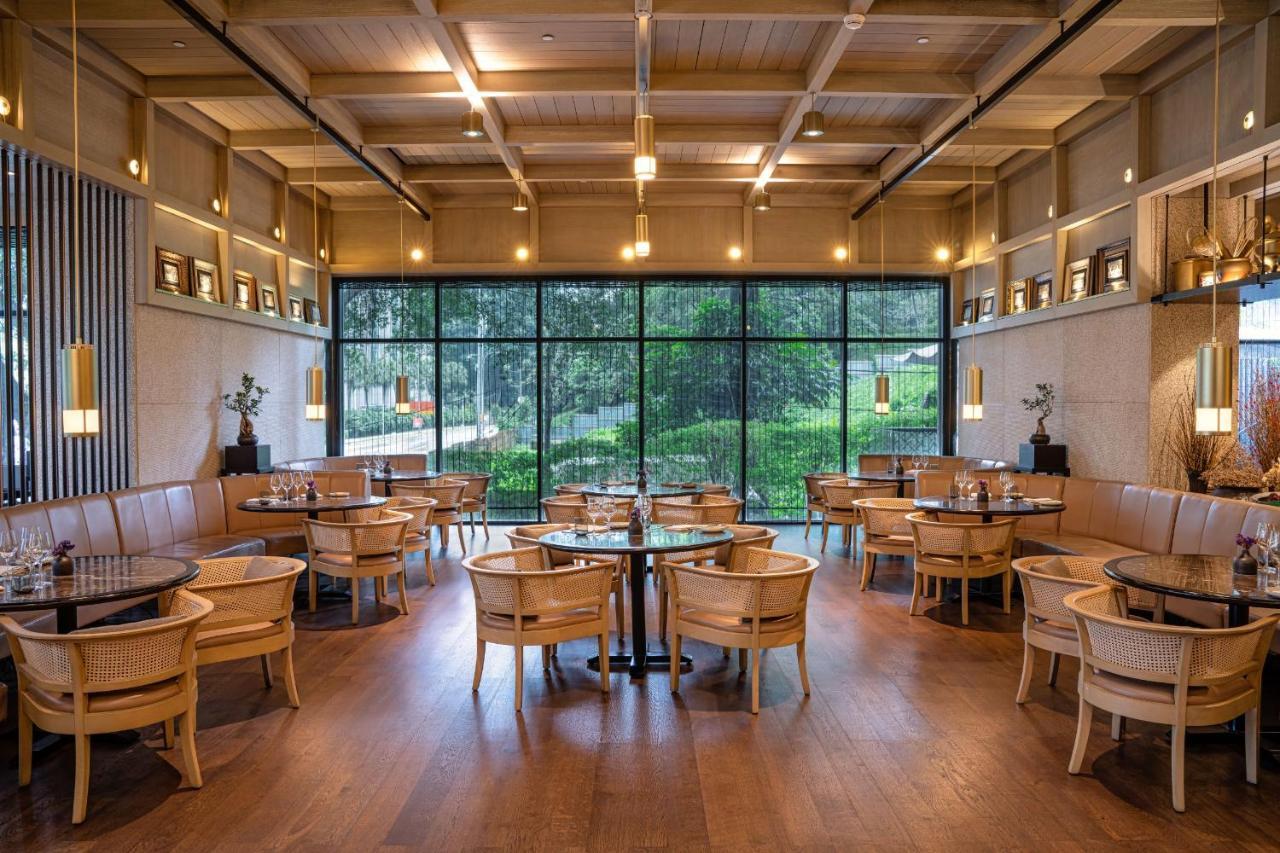 더 루마 호텔 앤 레지던스 쿠알라룸푸르 외부 사진 The photo shows the interior of a modern restaurant. It features wooden flooring, large windows that let in natural light, and an open layout. The seating consists of round tables surrounded by chairs, along with some cushioned booths. The decor has 